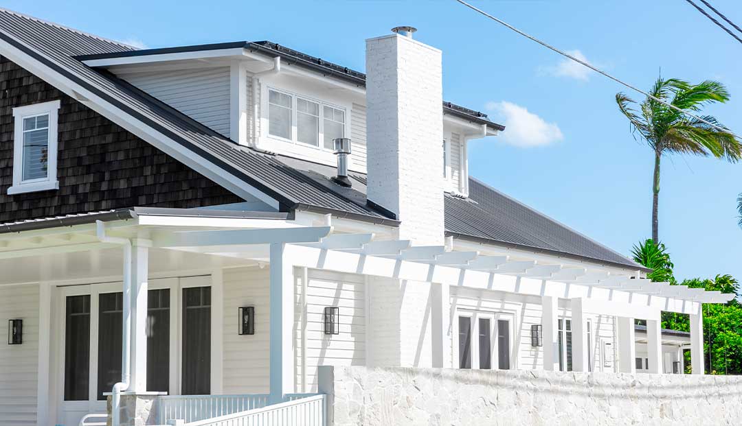 Manly Esplanade Project - classic white house with a black roof and tropical palm trees.