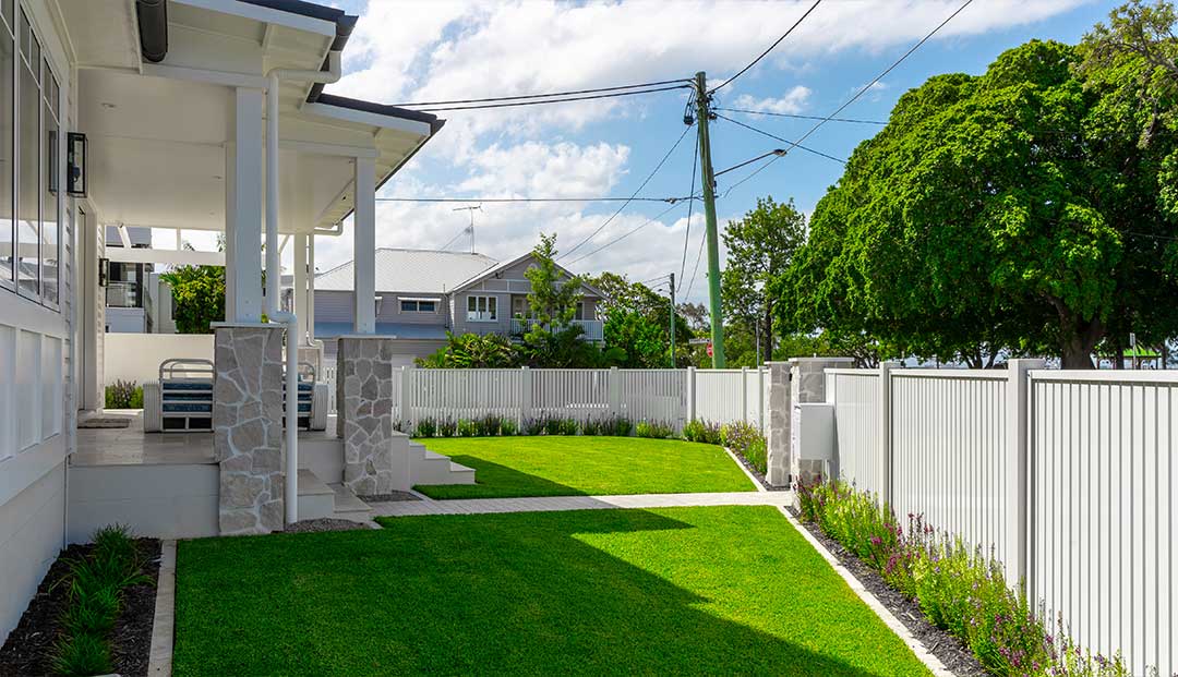 Manly Esplanade project veranda is a classic home with a manicured lawn and white fence.