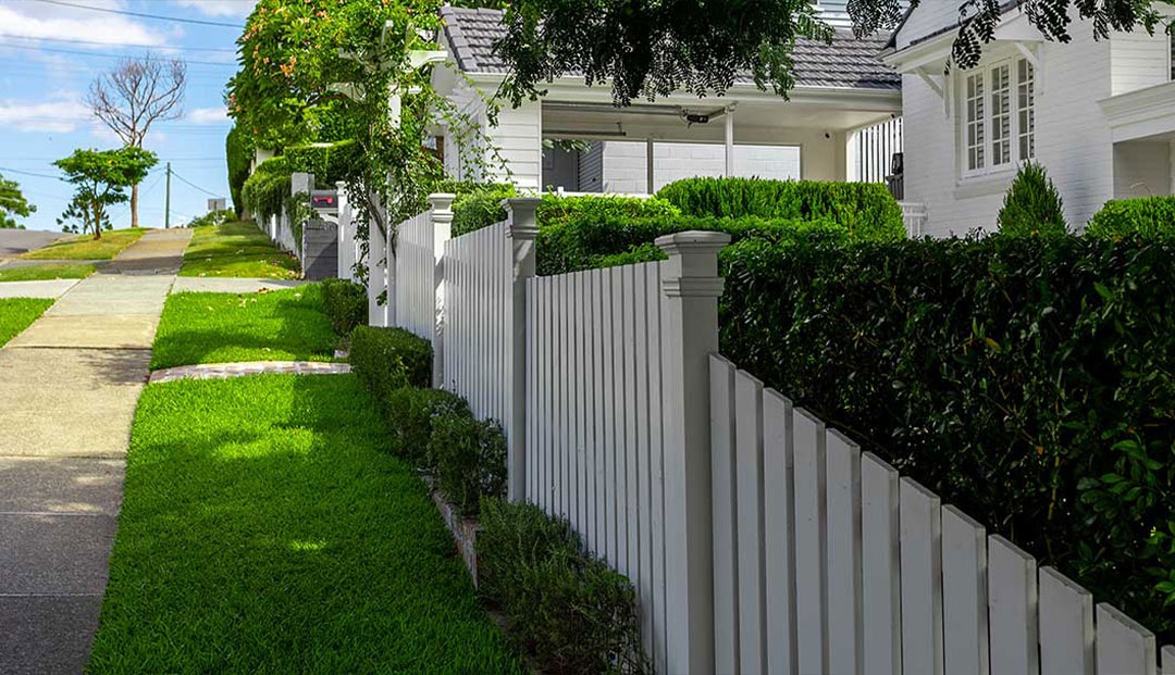 Brisbane city white picket fence along a lush suburban street.