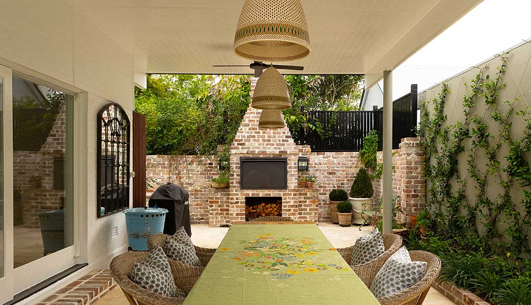 Outdoor dining area with pendant lights and a fireplace/pizza oven at Hazelmere Parade, Brisbane.